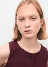 Chaleco de corte recto y diseño sin mangas, con cuello redondo y cierre frontal mediante botones. Presenta un estilo clásico y estructurado, ideal para combinar en conjuntos formales.