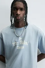 Camiseta de manga corta y cuello redondo, color celeste lavado, con estampado frontal en blanco que dice "The Mr. Rebel Dance".