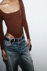 Body de manga larga con escote cuadrado, confeccionado en tejido elástico con cierre inferior mediante botones a presión.