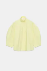 Camisa de algodón ZARA Woman Collection de color amarillo claro, con cuello alto y mangas abullonadas por debajo del codo. Presenta un diseño holgado y cierre frontal con botones ocultos por solapa.