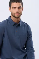 Remera polo de manga larga confeccionada en tejido jersey, con cuello clásico y cierre frontal de tres botones. Presenta un diseño liso con un pequeño logo bordado en el pecho y una etiqueta decorativa en el ruedo.