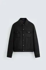 Cazadora de corte regular fit, color negro, confeccionada en tejido efecto ante. Presenta cuello solapa, manga larga con puños abotonados, bolsillos de plastrón con solapa en el pecho y bolsillos laterales en la costura de la cadera. Cierre frontal con botones a presión.