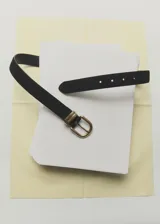 Cinturón negro de piel bovina con hebilla metálica dorada envejecida de forma ovalada.