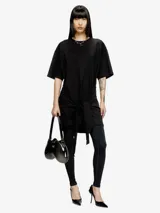 Vestido tipo camiseta de algodón orgánico, color negro, con mangas caídas y un lazo estilo bandana que se anuda en la parte delantera creando un efecto drapeado. Presenta un recorte ovalado bordado en el frente.