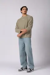 Buzo de cuello redondo y manga larga, confeccionado en tejido de punto acanalado de color negro. Presenta un diseño minimalista con un pequeño logo estampado en el pecho y un corte relajado.