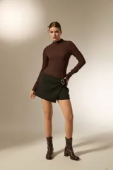 Short pollera negro de tiro alto, con diseño cruzado en el frente y detalle de hebilla metálica decorativa.