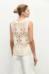 Top sin mangas confeccionado en tejido de crochet con patrón geométrico y floral, en color beige claro.