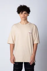 Remera blanca de corte oversize con mangas cortas y cuello redondo. Estampado pequeño en el frente con letras verdes.