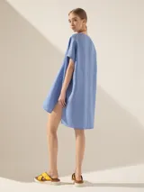 Túnica blanca de lino con corte asimétrico, mangas cortas y escote en V con pespuntes.