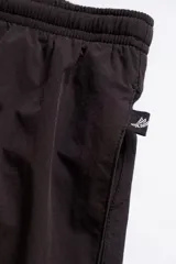 Short de baño negro con cintura elástica y cordón ajustable. Presenta bordados de sirenas en ambas piernas, bolsillos laterales y trasero con cierre. Incluye suspensor de malla fina hipoalergénico.