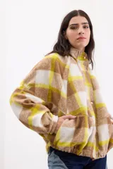 Campera bomber de paño italiano con estampa a cuadros en tonos beige, blanco y amarillo. Cuenta con cuello alto, cierre frontal con broches, bolsillos laterales y mangas murciélago con detalle de etiqueta de la marca.