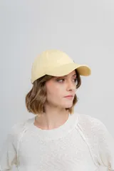 Gorra de visera curva color amarillo claro, con diseño clásico de paneles y ajuste posterior.