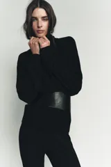 Jersey de punto liso color negro, con cuello subido y mangas largas de diseño murciélago con sisa ancha que se estrecha hacia la muñeca.