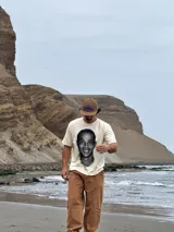 Remera de algodón color beige con estampa fotográfica frontal de Ronaldinho en blanco y negro. Presenta un corte boxy oversize, cuello redondo y mangas cortas.