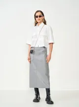 Falda midi gris de cuero sintético, con corte recto, bolsillos delanteros y cierre trasero.