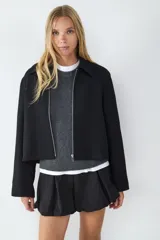 Campera corta negra con cierre frontal metálico, cuello camisero y mangas largas.