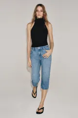 Jeans capri de tiro medio con diseño de cinco bolsillos, cintura con trabillas y cierre frontal con cremallera y botón. Presenta un acabado con efecto lavado.