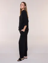 Blusa oversize color negro con caída fluida, escote redondo, bolsillo frontal en el pecho, mangas tres cuartos de hombro caído y costuras a la vista en contraste.