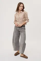 Jean de tiro medio y corte barrel con pierna amplia y ligeramente curva, estilo de cinco bolsillos en denim negro lavado.