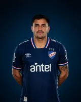 Camiseta de fútbol Umbro del Club Nacional de Football, modelo Away 2. Diseño azul oscuro con un patrón sutil texturizado, cuello en V con detalles tricolores en rojo, blanco y azul, y ribetes tricolores en los puños. Incluye el logo de Umbro, el escudo del club con tres copas y el sponsor principal en el frente.