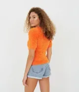 Blusa naranja de manga corta con textura de peluche sintético.