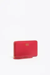 Billetera mediana de estructura rígida confeccionada en nylon color rojo, con cierre de cremallera perimetral y tirador de cinta con logo grabado. Presenta el logo de la marca aplicado en letras doradas en el frente.