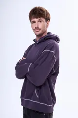 Buzo tipo canguro oversize color violeta oscuro con capucha, bolsillo delantero y estampa gráfica en la espalda con la palabra 'GLOBAL'. Presenta costuras decorativas en contraste.