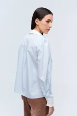 Camisa celeste a rayas con cuello clásico y puños blancos con volados.