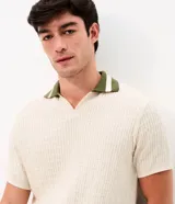 Remera polo de manga corta con textura retilínea, cuello polo en color verde contrastante y apertura frontal. Confeccionada en tejido de poliéster y algodón.