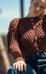 Cardigan marrón tejido a mano en lana merino, con mangas largas con trenzas 3D y botones de madera.