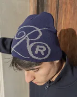 Gorro tipo beanie tejido en color azul marino con diseño de letras bordadas en gris en la parte frontal.