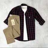 Camisa de manga larga a cuadros negros y rojos, con cuello clásico y cierre con botones.