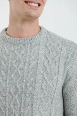 Sweater de tejido de punto color beige claro, con diseño de trenzas (aranes) en el frente y mangas de punto liso. Tiene cuello redondo.