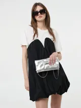 Vestido corto negro, estilo globo o balloon, con escote corazón pronunciado. Se lleva sobre una remera blanca de manga corta.