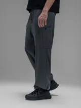 Pantalón cargo de corte oversize confeccionado en microfibra técnica. Presenta cintura elástica, bolsillos laterales y un bolsillo cargo con cierre de broche snap. Incluye un sistema de elásticos con tancas en los tobillos para regular la apertura y la silueta.