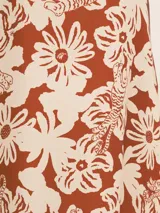 Vestido largo camisero de seda viscosa con estampado de flores y tigres en tonos naranja y blanco. Cuenta con botones nacarados, bolsillos, lazo para la cintura y aberturas laterales.