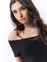 Top negro con estampado floral, escote off-shoulder, corte cruzado y mangas cortas.