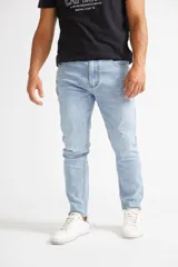 Jean de corte recto para hombre, en color celeste claro con efecto lavado. Presenta roturas localizadas, cintura regular con tiro medio, bolsillos clásicos y cierre frontal con botón.