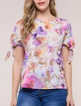 Blusa de gasa liviana con estampado floral en tonos violeta y rosado, cuello redondo y mangas cortas con detalle de lazo en los puños.