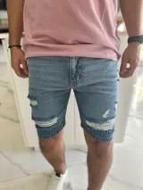 Bermuda de jean de corte ajustado con roturas y flecos en la parte frontal.
