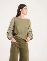 Pantalón de pana color verde oliva, de corte wide leg y largo al tobillo. Tiene cierre delantero con botón, bolsillos laterales y traseros.