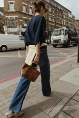 Bolso de hombro tipo mini saca con cuerpo en patchwork de denim en tonos azules. Posee una anilla metálica dorada como asa de mano y una correa bandolera extraíble.