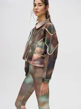 Calza deportiva 3/4 de tiro alto, confeccionada en lycra con un diseño estampado abstracto en tonos tierra, verdes y rosados.