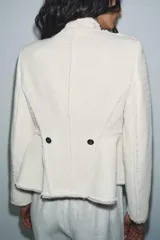 Blazer de cuello alto confeccionada en mezcla de algodón con textura tipo tweed. Presenta un diseño con acabados desflecados, cierre frontal con un solo botón y bajo con detalle peplum.