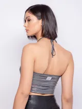 Top metalizado color champagne, sin mangas, con tirantes finos que se atan al cuello y abertura circular en el centro.