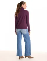 Polera de tejido fino, color rosado, con cuello alto, manga larga y detalle de tajo en los puños.