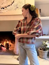 Camisa de corte holgado con estampado de cuadros en tonos rojos, marrones y beige. Presenta mangas abullonadas con puños elásticos y cuello camisero clásico.