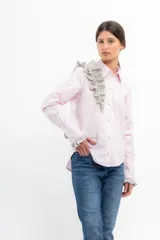 Camisa rosa pálido de manga larga con cuello camisero y volados grises en el frente y los puños.