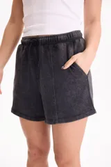 Short de felpa sin frisa con efecto acid wash color tostado, bolsillos laterales, tiro medio-alto, cintura elástica con cordón ajustable y costuras decorativas delanteras.