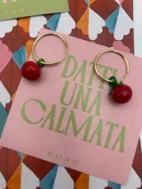 Par de aros dorados con dije colgante de cereza roja.